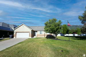 Ranch-style house with a garage and a front lawn