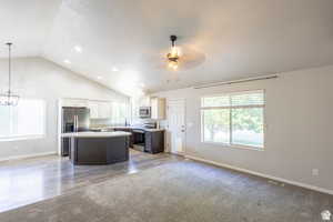 Kitchen with appliances with stainless steel finishes, a kitchen island, white cabinetry, hanging light fixtures, and ceiling fan