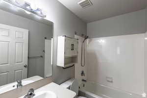 Full bathroom with sink, a textured ceiling, washtub / shower combination, and toilet