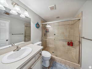 Bathroom featuring vanity, toilet, and a shower with door