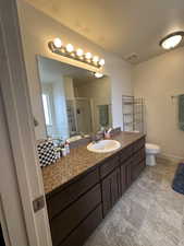 Bathroom with vanity, toilet, a textured ceiling, and walk in shower