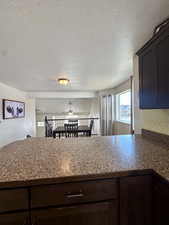 Kitchen featuring dark brown cabinets, kitchen peninsula, and ceiling fan