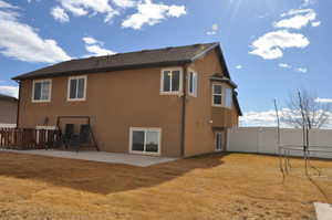 Rear view of house featuring a trampoline, a yard, and a patio