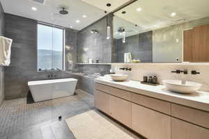 Bathroom with tile patterned flooring, tile walls, vanity, decorative backsplash, and separate shower and tub