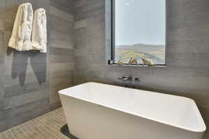 Bathroom featuring tile walls, a tub to relax in, and tile patterned floors