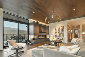 Living room featuring hardwood / wood-style flooring, a mountain view, a notable chandelier, and wood ceiling