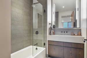 Bathroom featuring bath / shower combo with glass door and vanity