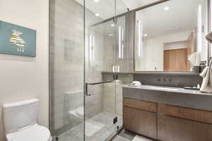 Bathroom with vanity, a shower with door, and toilet