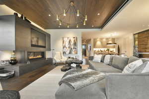 Living room with an inviting chandelier, wood ceiling, wood-type flooring, and a barn door