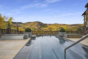 View of swimming pool featuring a hot tub, a mountain view, and a patio