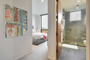 Bathroom featuring a wall of windows, a shower with door, and toilet