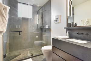 Bathroom with tile patterned flooring, vanity, a shower with shower door, and toilet