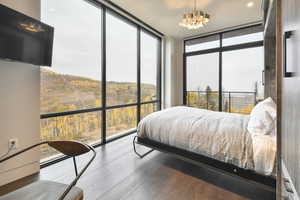 Bedroom with expansive windows, a chandelier, multiple windows, and hardwood / wood-style flooring