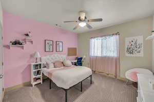 Carpeted bedroom featuring ceiling fan