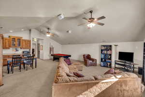 Living room featuring ceiling fan, lofted ceiling, light colored carpet, and pool table