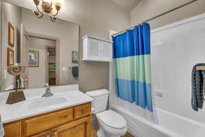 Full bathroom featuring shower / bathtub combination with curtain, vanity, a notable chandelier, and toilet