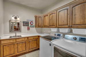 Washroom featuring separate washer and dryer, sink, and cabinets