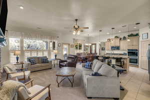 Tiled living room featuring sink and ceiling fan with notable chandelier