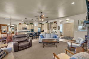 Living room with light tile patterned floors and ceiling fan with notable chandelier