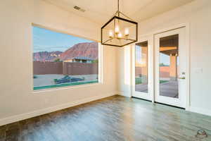 Unfurnished dining area with a mountain view, plenty of natural light, and wood-type flooring