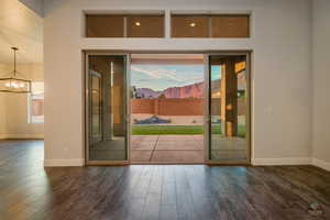 Doorway to outside with dark hardwood / wood-style flooring and a notable chandelier