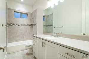 Full bathroom with vanity, tile patterned flooring, tiled shower / bath combo, and toilet