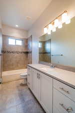 Full bathroom with vanity, tiled shower / bath, and toilet