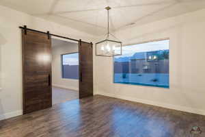 Unfurnished dining area featuring dark hardwood / wood-style flooring and a barn door