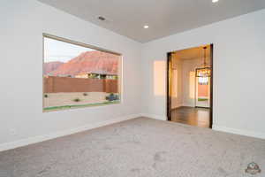 Carpeted empty room featuring a chandelier and a mountain view