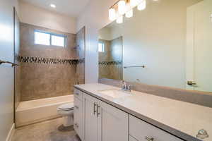 Full bathroom with tile patterned floors, vanity, toilet, and tiled shower / bath combo