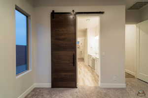 Corridor featuring a barn door and light carpet