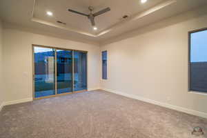 Unfurnished room with a tray ceiling, ceiling fan, and carpet