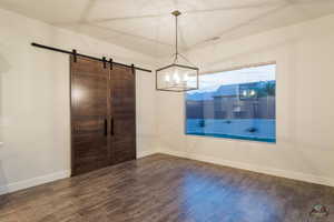 Unfurnished dining area featuring a barn door and dark wood-type flooring