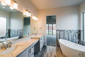 Bathroom featuring hardwood / wood-style floors, vanity, a bath, and tile walls