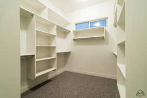 Walk in closet featuring dark carpet