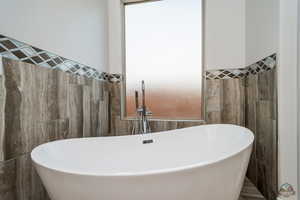 Bathroom featuring sink, tile walls, and a washtub