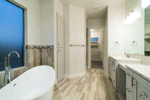 Bathroom with vanity, a washtub, and tile walls