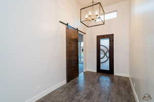 Entryway with a barn door, dark wood-type flooring, and a chandelier