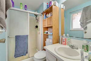 Bathroom featuring vanity, toilet, and an enclosed shower