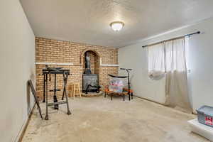 Living area with concrete flooring, a wood stove, and a textured ceiling