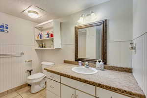 Bathroom featuring tile patterned floors, toilet, vanity, and a textured ceiling