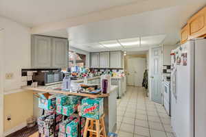 Kitchen with white appliances, a breakfast bar area, and kitchen peninsula