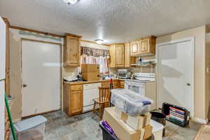 Kitchen featuring a textured ceiling and white appliances