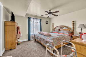 Carpeted bedroom featuring ceiling fan and a textured ceiling