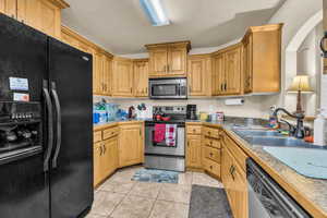 Kitchen featuring stainless steel appliances, sink, a textured ceiling, and light tile patterned floors