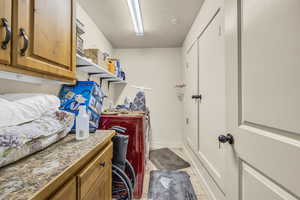 Laundry area featuring cabinets, light tile patterned flooring, washer and dryer, and a textured ceiling