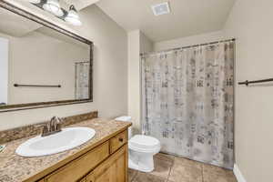 Bathroom featuring vanity, a shower with shower curtain, tile patterned floors, and toilet