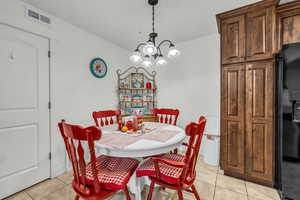 Tiled dining room featuring a notable chandelier