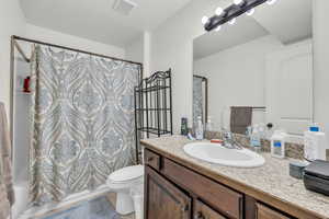 Full bathroom featuring vanity, shower / bath combination with curtain, and toilet