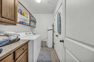 Clothes washing area featuring separate washer and dryer and cabinets